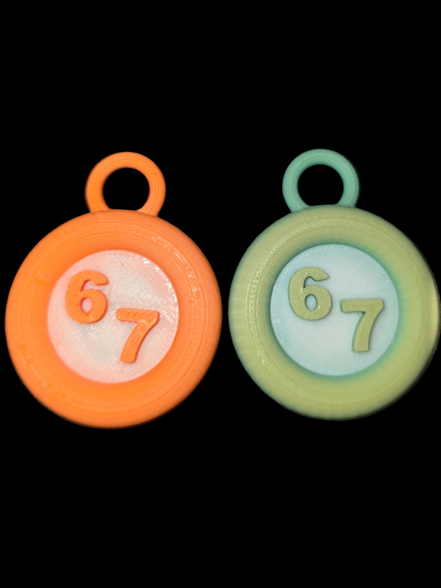 Two round keychains with numbers '67' on a black background