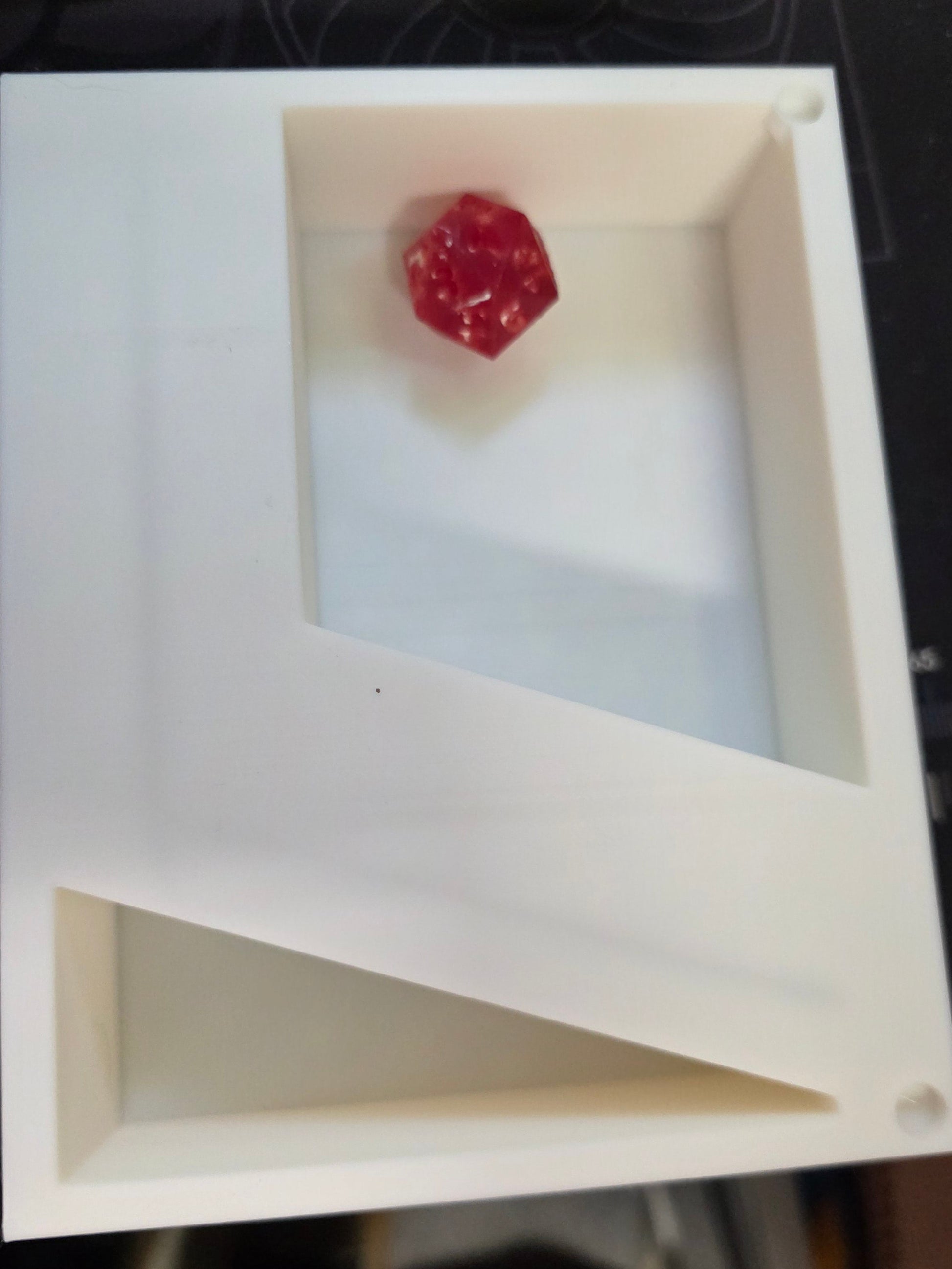Small red object on a white square platform with a blurred background